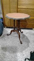 Front view of the round wood side table showing scalloped edge top and tripod base with claw feet.