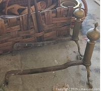 Two vintage metal fireplace andirons with decorative finials and three support legs.