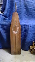 Front view of the vintage wooden ironing board showing the floral wreath decoration and wood grain