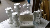 Full view of all items including candleholders, 'LOVE' sign, fruit basket with white orbs, angel candleholder figurine, and decorative box all on a white washed wooden surface.