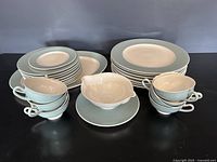 Full view of stacked plates, cups, gravy boat, and serving platter showing the lot contents and blue and white color of porcelain set.
