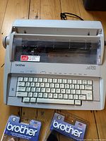 Brother Correctronic GX-6750 electronic typewriter with visible keyboard and typing area, two sealed Brother ribbons in original packaging visible in foreground