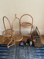 Photo showing three-tier wooden folding plant stand with spiral round platforms along with wooden divided caddy, metal tray, two vases, soap, lotion, and glass plant mister on a blue patterned rug.