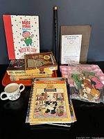 Wide view showing assorted kids' items including puzzles, books, mug, fife, and craft supplies