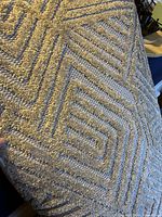 Close-up showing the beige geometric textured pattern of the rug, highlighting pile and weave details.