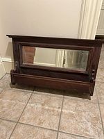 Front view of rectangular wooden framed mirror with beveled glass, showing the overall design and condition on tiled floor.