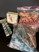 Overview of the vintage baby cake decorating supplies including bags of plastic baby carriage toppers, figurine candles, and plastic numbers, with napkins and party poppers to the side.
