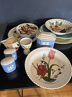 Full view of the variety of vintage ceramic dishes and pottery including fruit plates, cream pitcher, egg cup, blue salt and pepper, and lidded box.
