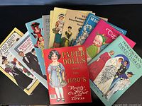 Photo showing a selection of colorful vintage paper doll books with illustrated covers.