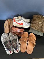 Overview of lot showing clothing items, shoes (Nike, Rothy's, sandals), belts, and leather clutch