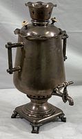 Full front view of the antique samovar highlighting the overall shape, handles, spigot, and base.
