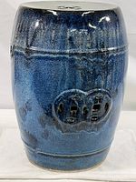 Front view of the dark blue ceramic garden drum stool showing rounded shape and decorative medallion vent cutout.