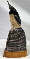 Left profile view of the hand carved bird sculpture showing black and natural horn coloration with carved feather details and teak base.