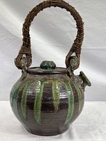 Full view of the large ceramic teapot showing the woven vine handle, shape, spout and lid with knob.
