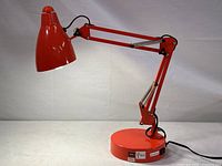 Adjustable orange desk lamp with articulated arm and round base, showing overall lamp structure and color.
