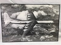 Front view of the entire metal framed Convair B-36 aircraft print showing the plane in flight from above, clouds and terrain below.