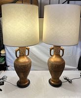 Two vintage brass table lamps with off-white fabric shades, showing overall appearance and height comparison