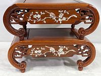 Front view of two stacked wooden stands with abalone shell bird and floral inlays on front panels