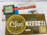 Monopoly and Clue original boxes showing wear, with Clue box front visible including vintage characters and game title.