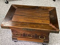 Top view of rectangular oak table with a wood panel center and decorative metal corner pieces.