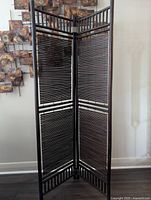 Full view of the three-panel bamboo privacy screen standing upright against a wall. Shows the overall design and structure.