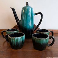 Front and top view of teapot with four mugs surrounding it, showing colors and condition.