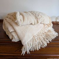 Rolled bedspread showing thick weave, chenille floral and looped texture and fringe.