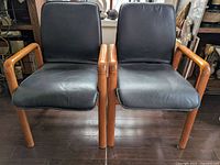 Front view of two chairs side by side on hardwood floor with art in background