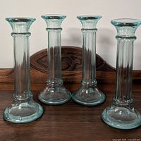 Set of 4 vintage E V Italian glass candle holders shown standing on wooden surface with light aqua tint and flared tops.