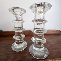 Pair of candlestick holders on wood surface, front view