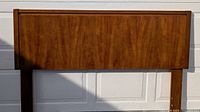 Front view of wooden headboard showing rectangular panel with wood grain and framed border