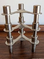Front angled view showing one stacking candleholder with triangular plate and three candle cups.