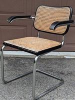 Full side/front view of chrome cantilever Cesca armchair with cane seat/back and black wood armrests