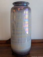 Front view of tall cylindrical vase showing gradient iridescent glaze with purples and light horizontal stripes