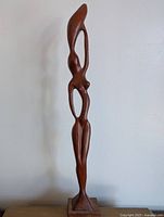 Full view of the tall carved wooden female figure sculpture.