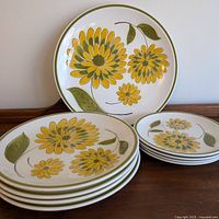 Four dinner plates and four lunch plates with a floral design arranged on a wooden surface