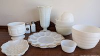 Wide view showing all milk glass items arranged: vase, plates, bowls, salt and pepper shakers.