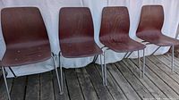 Four stacked plywood chairs with tubular metal legs, photo showing overall set and condition