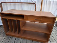 Wooden rectangular media stand with one drawer, vinyl record storage slots, and open shelving underneath.