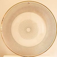 Top view of the round glass platter showing the gold geometric floral and mesh design.