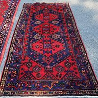 Full view of runner laid flat outdoors showing red central field with navy geometric medallions and multiple borders.