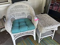 White painted wicker chair with blue cushion and white painted wicker side table next to it showing full set
