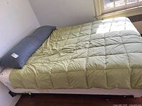 Full view of the body pillow on the bed with light green comforter