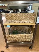 Overview photo showing woven baskets with various kitchen items, jars on lower shelf, cookware and utensils on upper shelf
