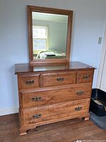 Front view of the wooden dresser with mirror, showing four drawers and mirror mounted on top.