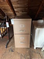 Front view of beige metal 2-drawer file cabinet showing handles and label holders on drawers.