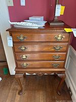 Full frontal view of the wooden flatware chest showing all four drawers with brass handles and decorative top with items on it.