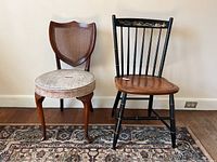 Photo showing two chairs side by side, focus on the vintage shield back chair with cane and padded seat on left.