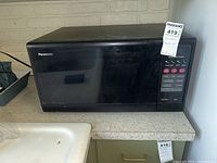 Black Panasonic microwave oven sitting on countertop showing front and right side with control panel.