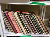 Full shelf view showing a collection of approximately 30+ vinyl LPs with varied album covers including different artists and genres.